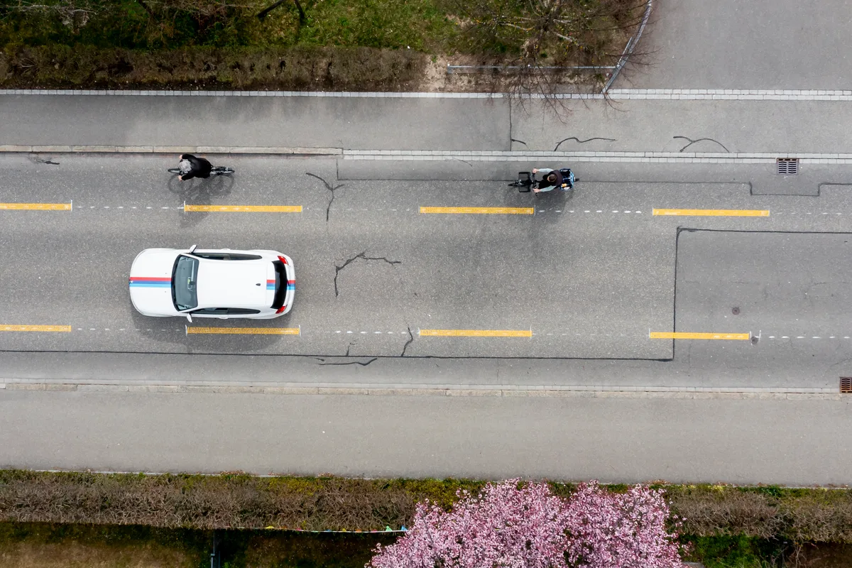 2021 wurde auf der Brandstrasse ein Pilotprojekt mit einem Veloweg  vorgestellt. Blick von oben auf eine Strasse mit Auto- und Velospur.